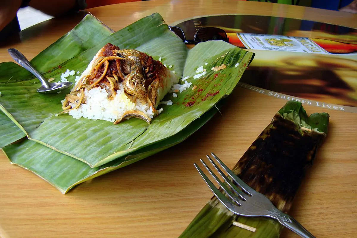 Nasi lemak served on banana leaf with rice, fried anchovies and fish