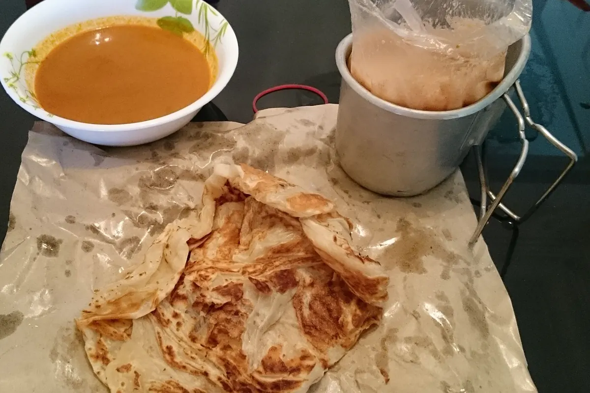 Flaky roti prata served with curry and a cup of tea